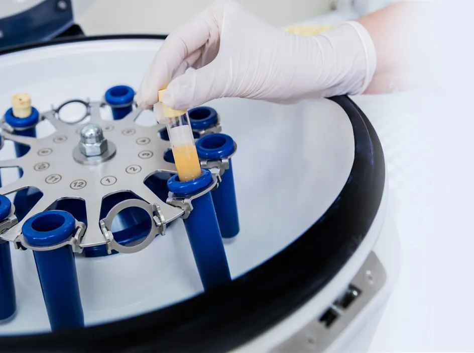 A clinician placing a prepared blood sample into a medical centrifuge